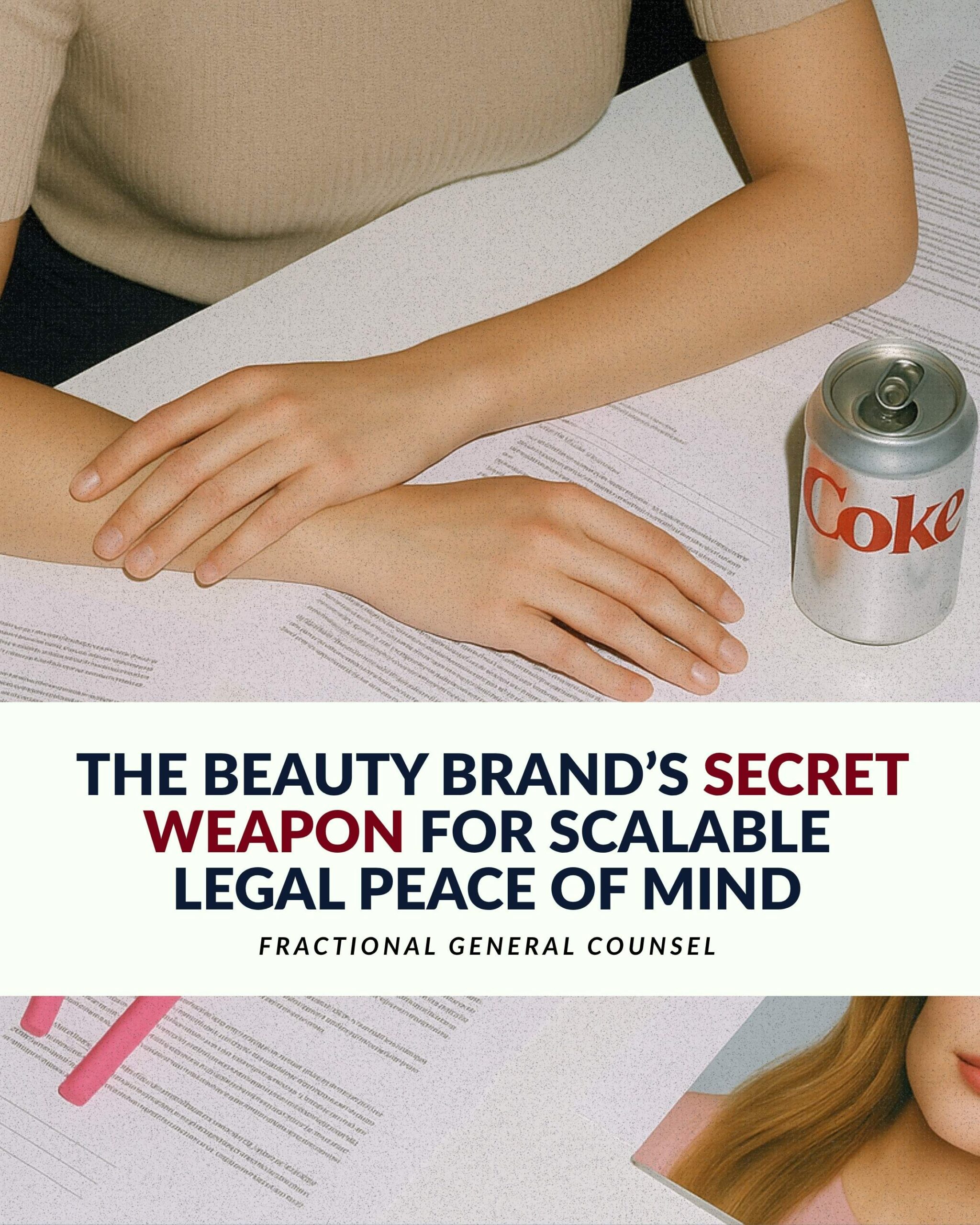 Woman sitting at a desk with legal documents and a Diet Coke can, promoting fractional general counsel services for beauty brands.
